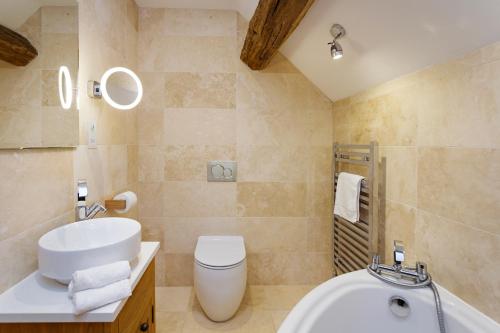 a bathroom with a sink and a toilet and a tub at 1 Luzon Dove Barn in Stoke on Trent