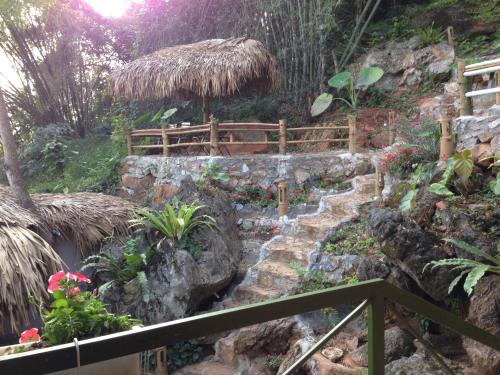 a garden with a waterfall and a wooden bridge at Green Hill Hostel & Tour in Ha Giang
