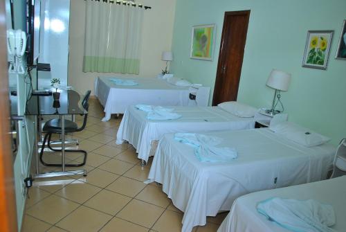 Zimmer mit 3 Betten und weißer Bettwäsche in der Unterkunft Hotel Industrial Contagem in Contagem