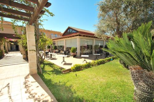 a building with a patio and a grass yard at Mar Hotels Playa Mar & Spa in Port de Pollensa