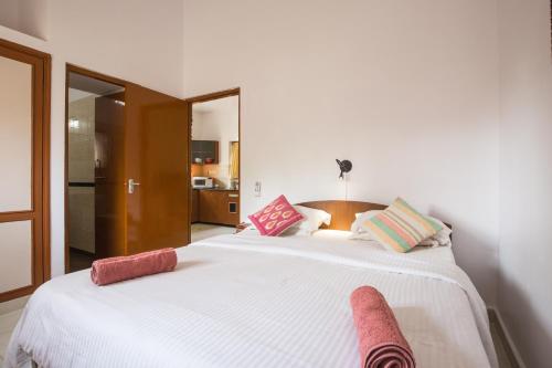 a bedroom with a large white bed with pink pillows at Tobias Villas in Cavelossim