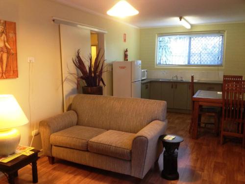 a living room with a couch and a kitchen at Coconut Palms On The Bay in Hervey Bay