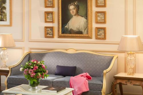 a living room with a couch and a portrait of a woman at Auberge du Jeu de Paume in Chantilly