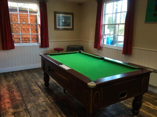 a pool table in a room with windows at The White Hart pub and rooms in Cranleigh