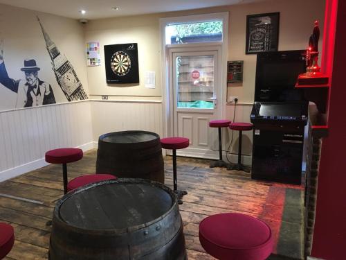a room with barrels and stools and a clock at The White Hart pub and rooms in Cranleigh