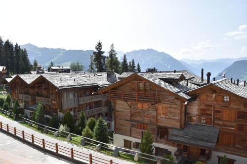 a group of wooden buildings with mountains in the background at Bruyères B22 in Verbier