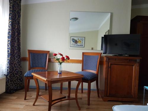 Zimmer mit einem Tisch, 2 Stühlen und einem TV in der Unterkunft Pension Oase in Berlin