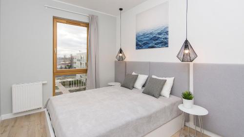 a white bedroom with a bed and a window at Glow Apartments, Apartament Mila Baltica in Gdańsk