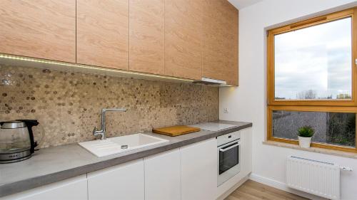 a kitchen with white cabinets and a sink and a window at Glow Apartments, Apartament Mila Baltica in Gdańsk