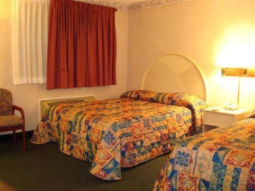 una habitación de hotel con 2 camas y una silla en O'Hare Inn & Suites en Schiller Park