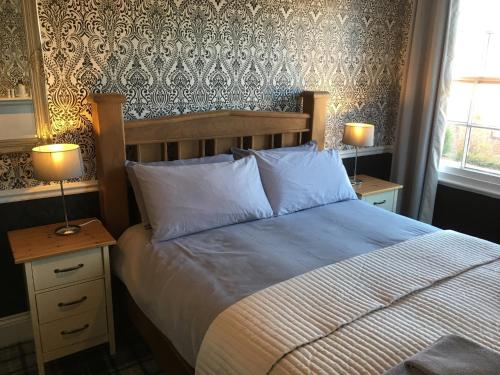 a bedroom with a bed with two lamps on tables at The White Hart pub and rooms in Cranleigh