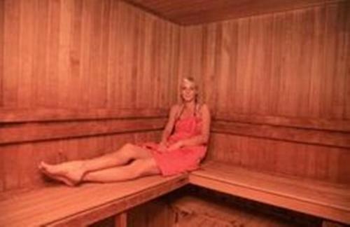 a woman sitting on a bench in a sauna at Hotel Praha in Boží Dar