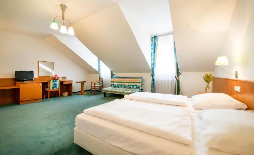 ein Hotelzimmer mit 2 Betten, einem Schreibtisch und einem Zimmer in der Unterkunft Hotel Dvorak in Budweis