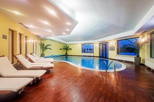 a swimming pool in a room with chairs and a table at Hotel Bellevue - Half Board in Pamporovo