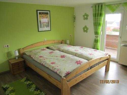 ein Holzbett in einem Schlafzimmer mit grünen Wänden in der Unterkunft Ferienhaus Ahlborn in Uslar