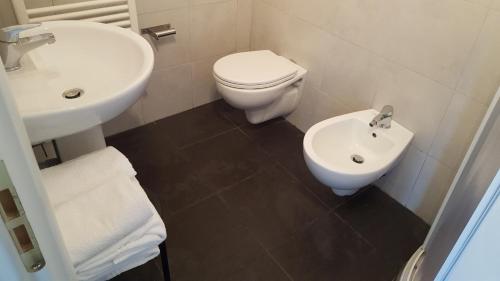 a white bathroom with a toilet and a sink at Hotel Sauro in Viareggio
