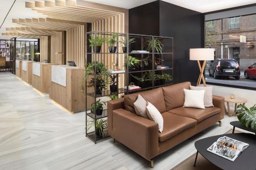 a lobby with a brown couch and plants at Melia Madrid Serrano in Madrid