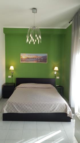 a green bedroom with a bed and a chandelier at Hotel Sauro in Viareggio