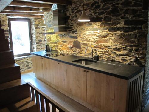 a kitchen with a sink and a stone wall at Casa do Talasnal in Lousã
