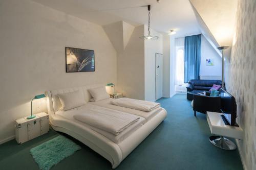 a bedroom with a large white bed and a chair at Hotel am Berg in Frankfurt/Main