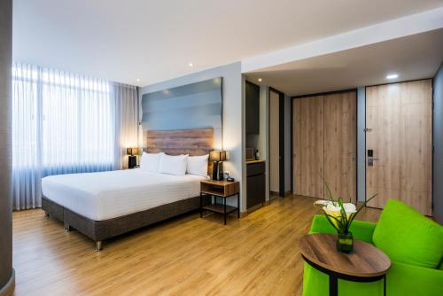 a hotel room with a bed and a couch at La Quinta by Wyndham Medellin in Medellín