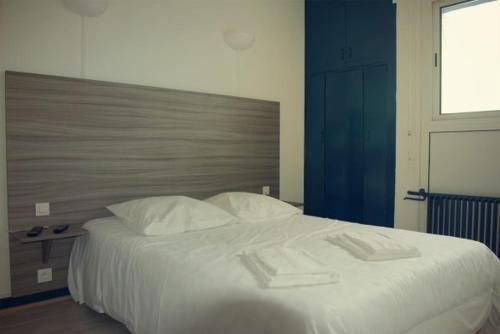 sypialnia z dużym łóżkiem z białą pościelą i poduszkami w obiekcie Océan Forêt w mieście Les Mathes