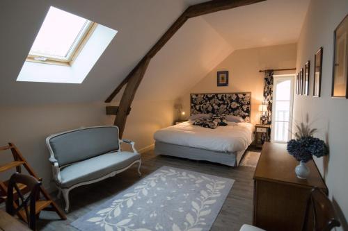 1 dormitorio en el ático con 1 cama y 1 silla en Domaine de Montgenoux, en Prissac