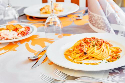 a plate of pasta on a table with fork and knife at Hotel Dolcevita in Cesenatico