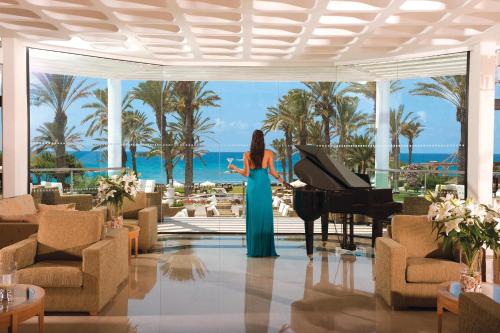 a woman in a blue dress playing a piano in a hotel lobby at Constantinou Bros Asimina Suites Hotel in Paphos