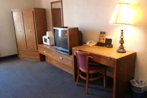 Habitación de hotel con escritorio, TV y lámpara. en State Line Inn, en Hagerstown