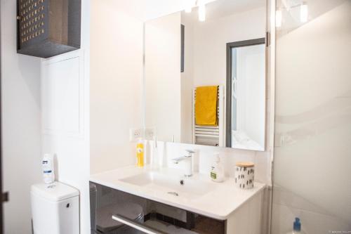 une salle de bain blanche avec un lavabo et un miroir dans l'établissement Place du Palais 3°, à Bordeaux