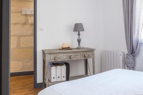 une table avec une lampe à côté d'un lit dans l'établissement Place du Palais 3°, à Bordeaux