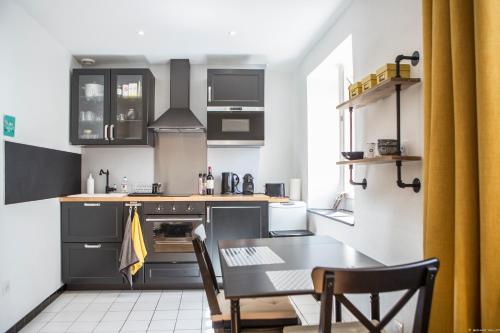 une cuisine avec des armoires noires et une table avec des chaises dans l'établissement Place du Palais 3°, à Bordeaux
