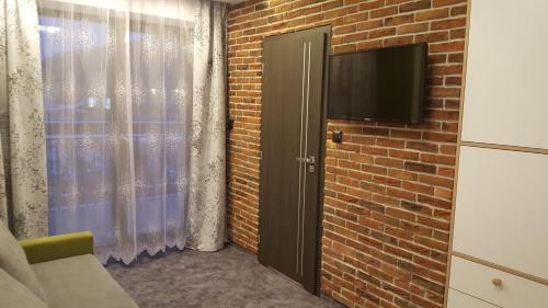 a room with a brick wall and a door with a television at Willa Karo in Muszyna
