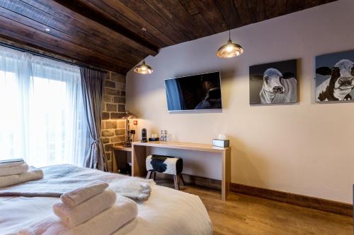 a bedroom with a bed and a desk and a television at The Cow Dalbury in Dalbury Lees