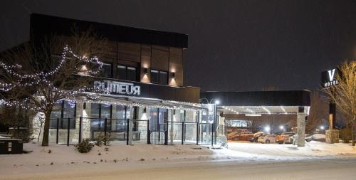a building with lights in the snow at night at Hotel V in Gatineau