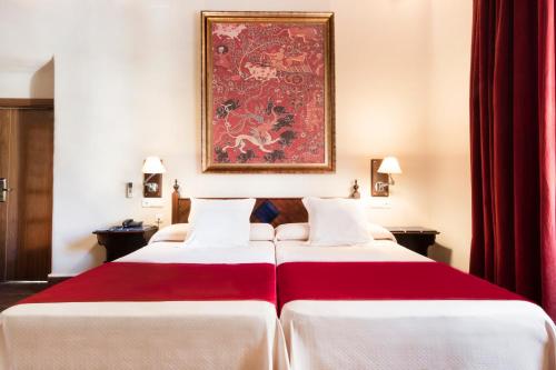 two beds in a hotel room with a painting on the wall at Casa Palacio Pilar del Toro in Granada
