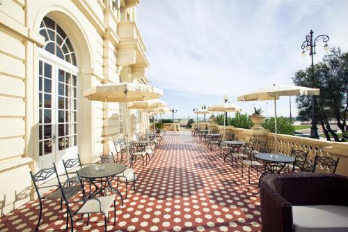 an outdoor patio with tables and chairs and umbrellas at Grand Hotel Cesenatico in Cesenatico