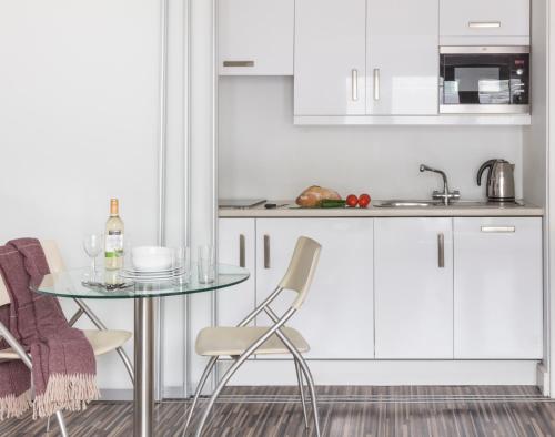 a kitchen with white cabinets and a table and chairs at SACO Holborn – Lamb’s Conduit St in London