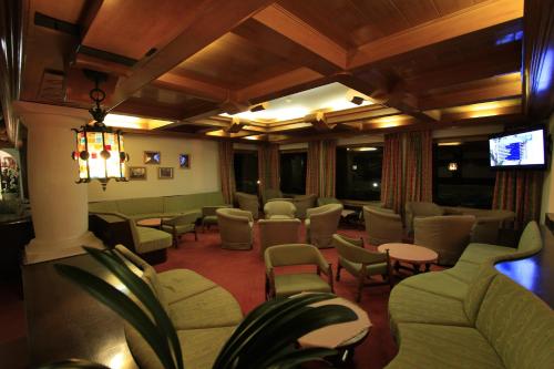 a waiting room with chairs and tables and a tv at Hotel Regina Delle Dolomiti in Panchia
