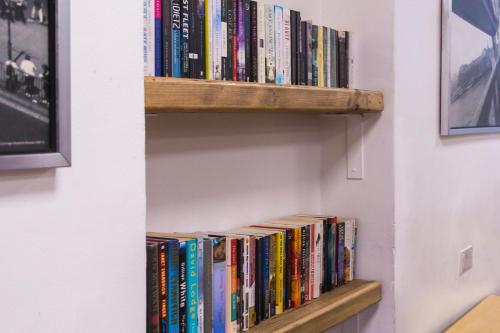 una mensola piena di libri su un muro di Smart Russell Square Hostel a Londra