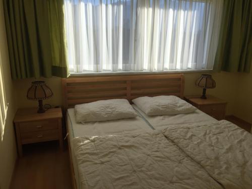 a bedroom with a bed with two lamps and a window at Haus Daniela in Drobollach am Faaker See