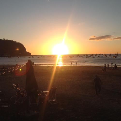 a group of people on the beach at sunset at Hostal Villas Mexico in San Juan del Sur