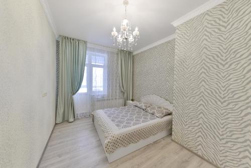 a bedroom with a bed and a chandelier at Apartments 144- Expo, Mega Silky Way in Astana