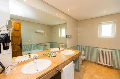 Un baño con dos lavabos y un inodoro. en Parador de Ribadeo, en Ribadeo