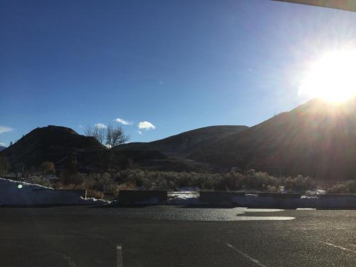 a sun setting over a parking lot with mountains in the background at Riverside Motel Cache Creek in Cache Creek