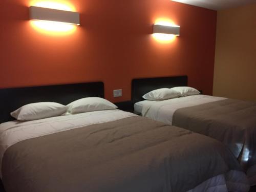 two beds in a room with two lights on the wall at Riverside Motel Cache Creek in Cache Creek