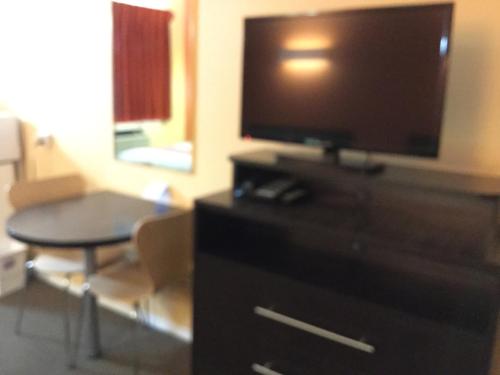 a living room with a flat screen tv on a dresser at Riverside Motel Cache Creek in Cache Creek