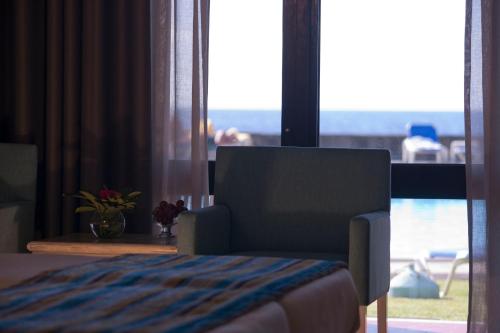 a bedroom with a chair and a large window at Estalagem do Mar in São Vicente