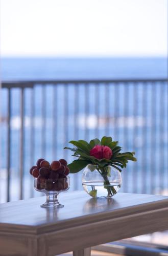 a table with a vase of flowers and a bowl of fruit at Estalagem do Mar in São Vicente